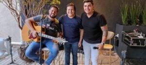 Cantores Victor Jr e Gabriel cantando e tocando violão com o músico Giovani na Mostra Kzulo